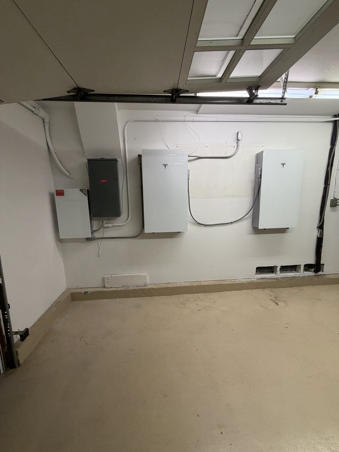 A Tesla Powerwall battery storage unit installed by GreeMpower on an exterior wall