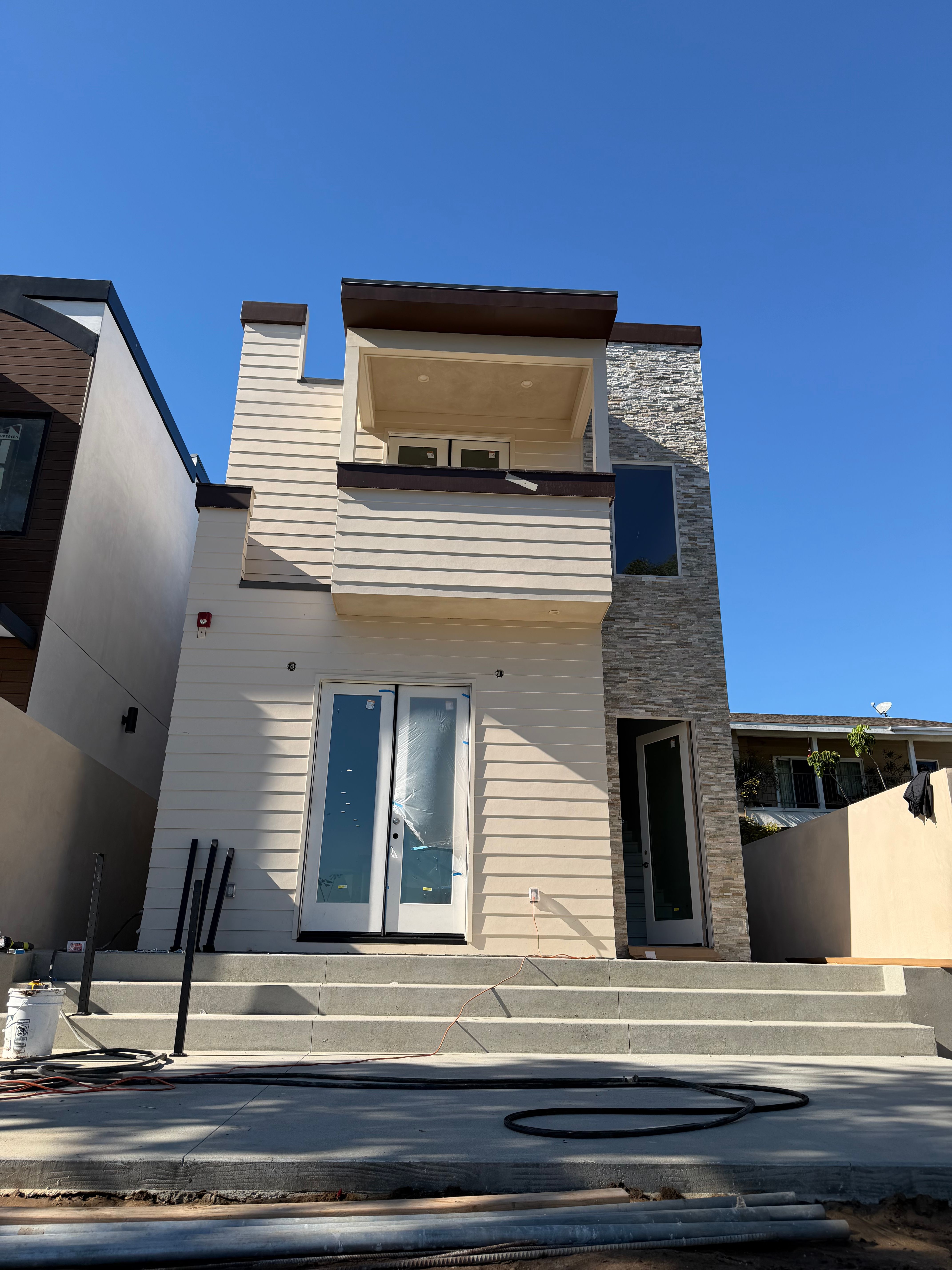 New residential construction with the exterior finished, protective film still on the entry doors and the site not yet landscaped.