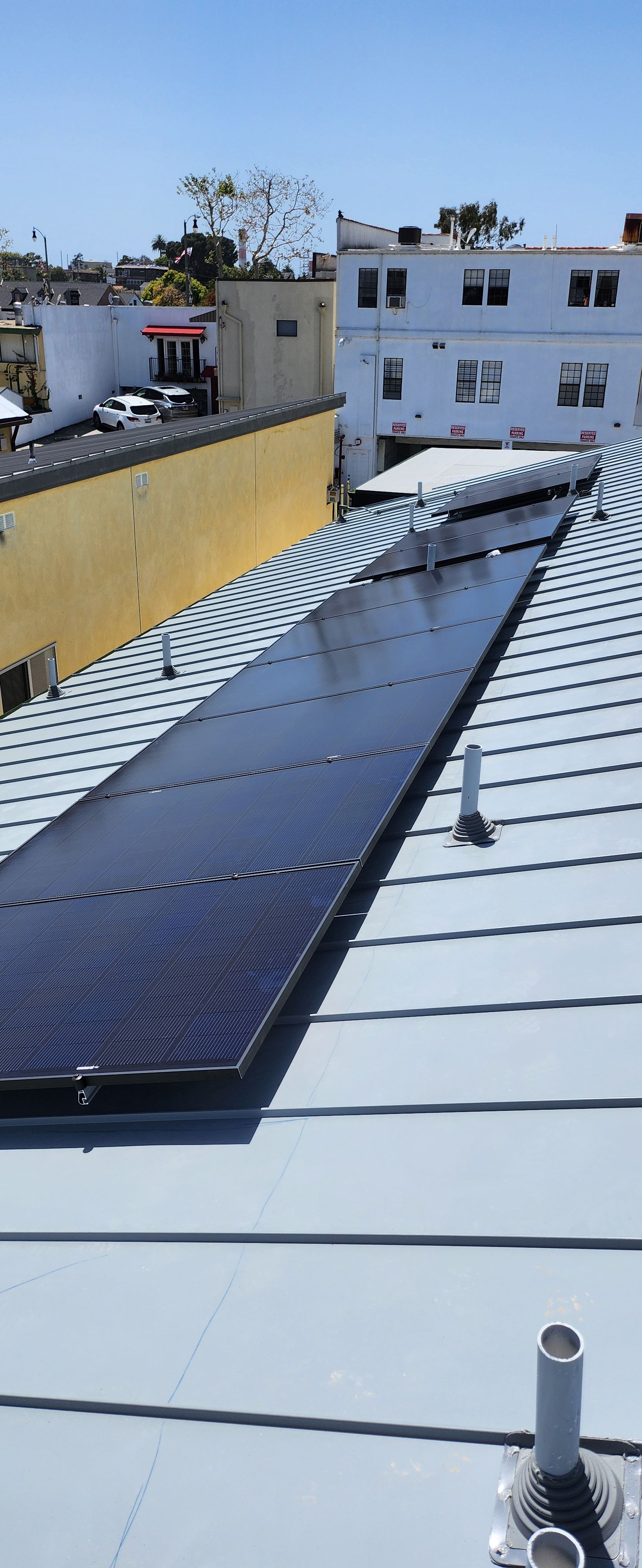 Completed photovoltaic array clamped to the seams of a standing-seam metal roof on a new residential building.